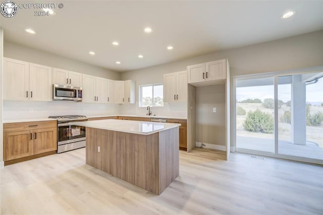 kitchen with sink, light hardwood / wood-style flooring, stainless steel appliances, a center island, and white cabinets