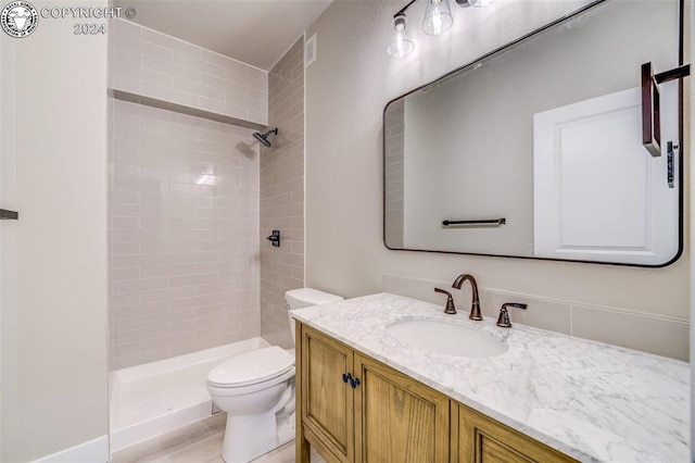 bathroom featuring vanity, toilet, and tiled shower