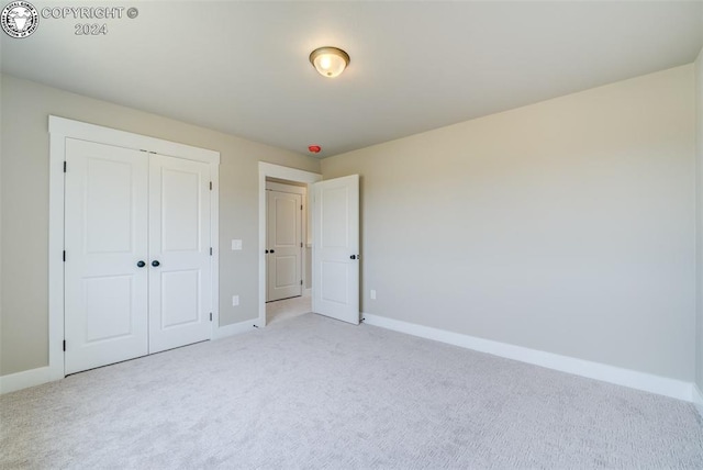 unfurnished bedroom with a closet and light carpet