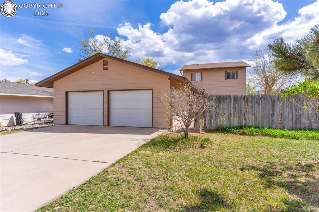 view of front of house featuring a garage, an outdoor structure, and a front lawn