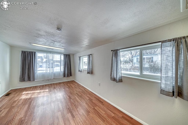 empty room with wood-type flooring and a textured ceiling