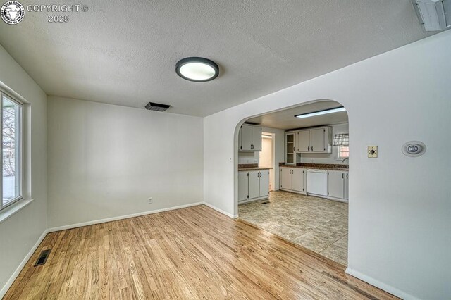 unfurnished living room featuring light hardwood / wood-style flooring and a textured ceiling