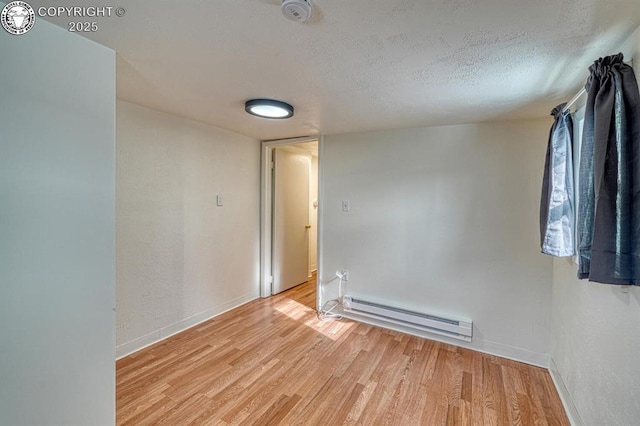 empty room with light hardwood / wood-style flooring, a textured ceiling, and baseboard heating