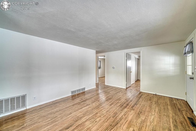 unfurnished room featuring a textured ceiling and light hardwood / wood-style flooring