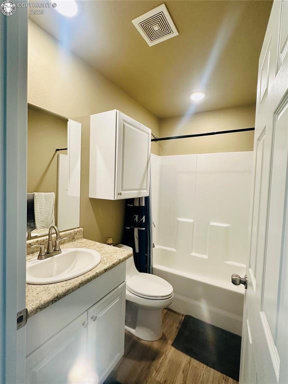 248 Indian Hills Rd, Florence, CO 81226 - bathroom featuring vanity, toilet, visible vents, tub / shower combination, and wood finished floors