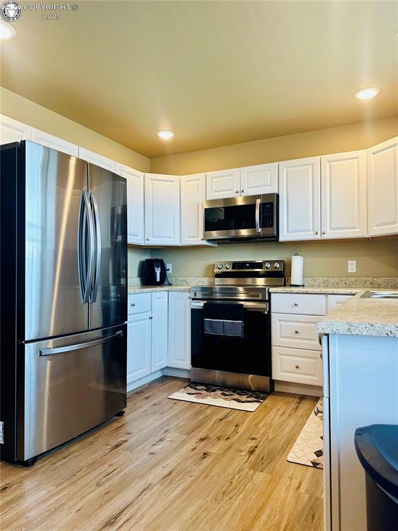 248 Indian Hills Rd, Florence, CO 81226 - kitchen with stainless steel appliances, recessed lighting, light wood-style floors, and white cabinetry