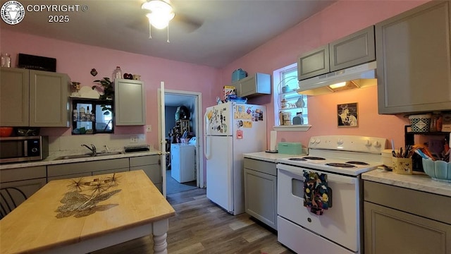 1318 Spruce St, Pueblo, CO 81004 - kitchen featuring white appliances, under cabinet range hood, gray cabinetry, light countertops, and separate washer and dryer