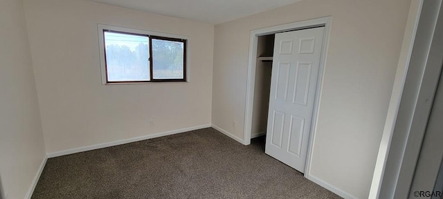 unfurnished bedroom with dark carpet and a closet