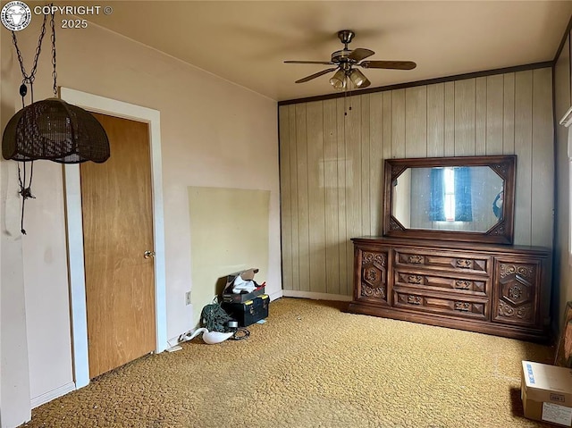 interior space with ceiling fan, wooden walls, and carpet floors