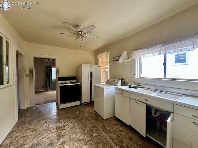 kitchen featuring sink, white refrigerator, gas stove, white cabinets, and washer / clothes dryer