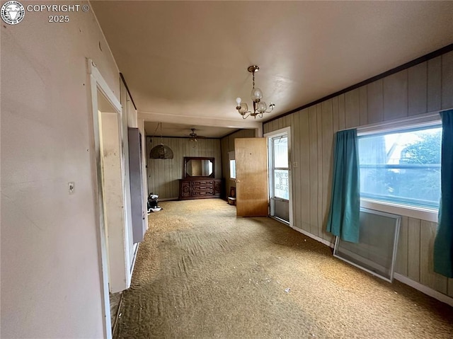 unfurnished living room with a chandelier and wood walls