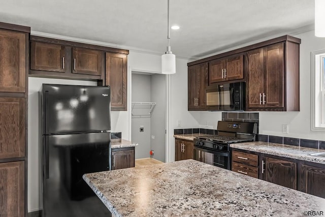kitchen featuring crown molding, light stone counters, decorative light fixtures, dark brown cabinets, and black appliances
