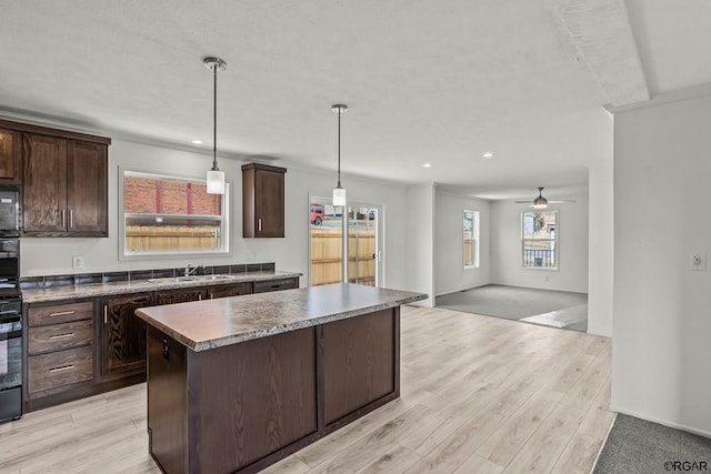 kitchen featuring dark brown cabinets, a center island, sink, and hanging light fixtures