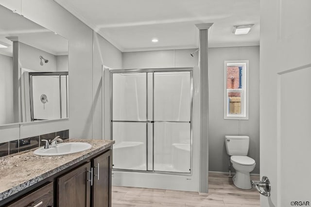 bathroom featuring crown molding, vanity, wood-type flooring, toilet, and walk in shower