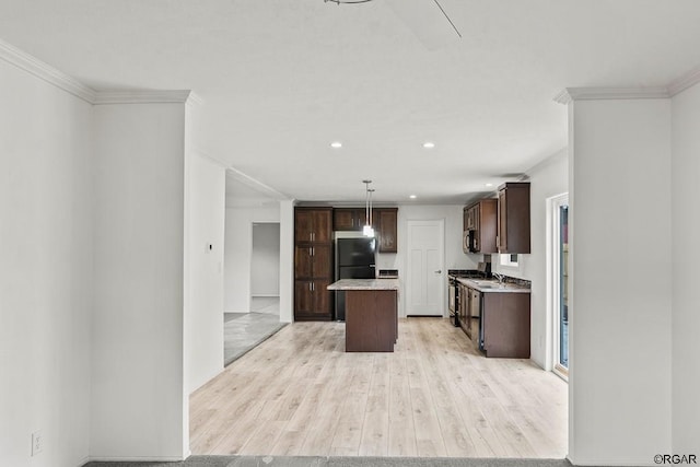 kitchen featuring pendant lighting, sink, light hardwood / wood-style flooring, black refrigerator, and a center island