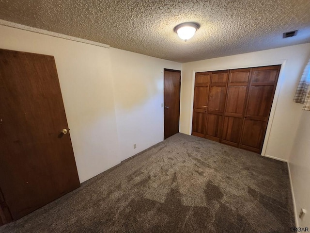 unfurnished bedroom featuring dark carpet, a closet, and a textured ceiling