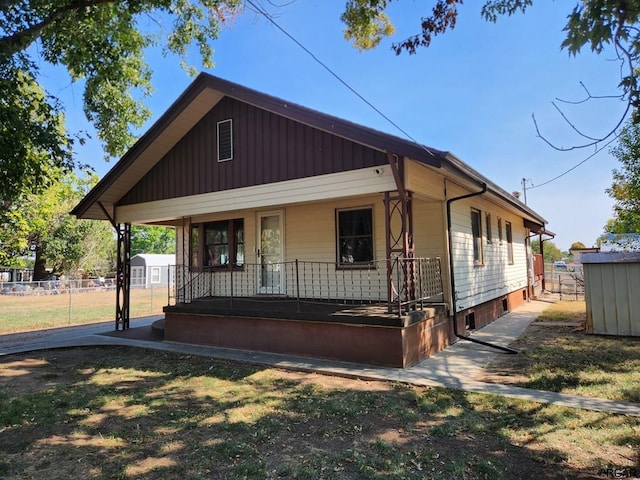 bungalow-style home featuring a porch and a storage shed