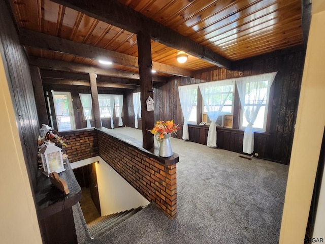 interior space with beamed ceiling, wooden ceiling, a healthy amount of sunlight, and wood walls