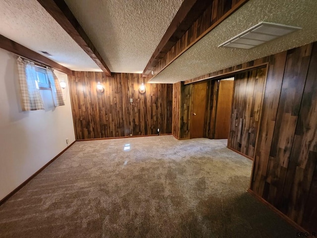 basement with carpet, a textured ceiling, and wood walls