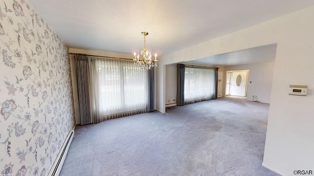 empty room with baseboard heating, a chandelier, and carpet flooring