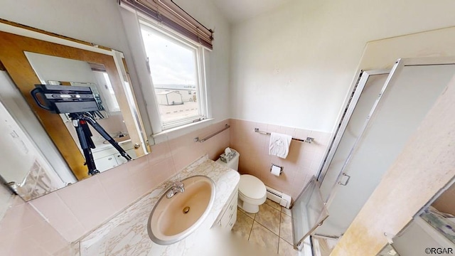 bathroom featuring sink, baseboard heating, tile walls, tile patterned flooring, and toilet