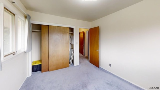 unfurnished bedroom with light colored carpet and a closet