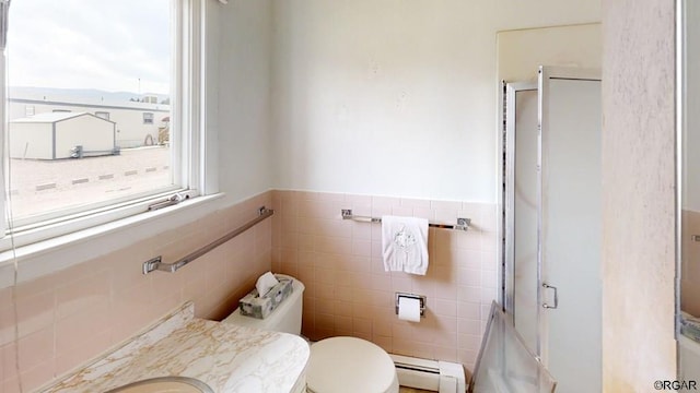 bathroom featuring tile walls, a baseboard heating unit, vanity, a shower with shower door, and toilet