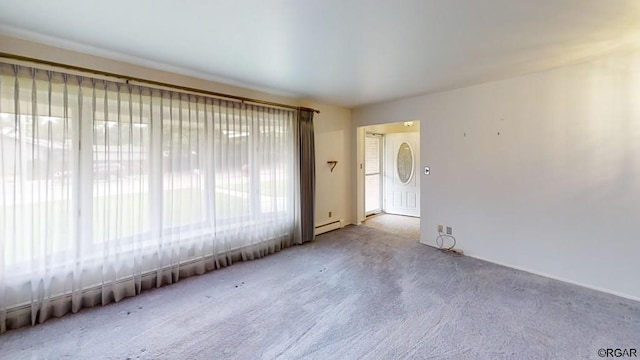 unfurnished room featuring a baseboard radiator, light carpet, and a wealth of natural light