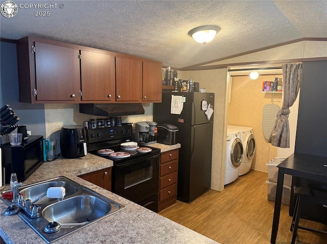 kitchen with washing machine and clothes dryer, sink, black appliances, light hardwood / wood-style floors, and exhaust hood