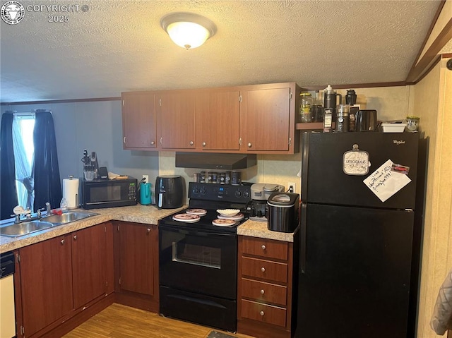 kitchen featuring sink, black appliances, light hardwood / wood-style floors, and a textured ceiling