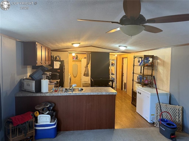 kitchen with fridge, kitchen peninsula, vaulted ceiling, and a textured ceiling