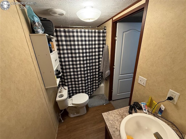 full bathroom with hardwood / wood-style floors, shower / tub combo with curtain, vanity, toilet, and a textured ceiling