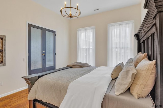 bedroom with an inviting chandelier, hardwood / wood-style floors, and french doors