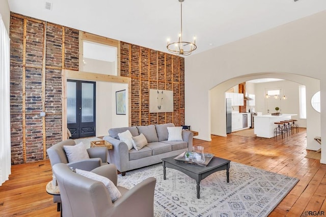 living room with brick wall, light hardwood / wood-style flooring, and a notable chandelier