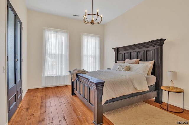 bedroom with an inviting chandelier, light hardwood / wood-style floors, and multiple windows