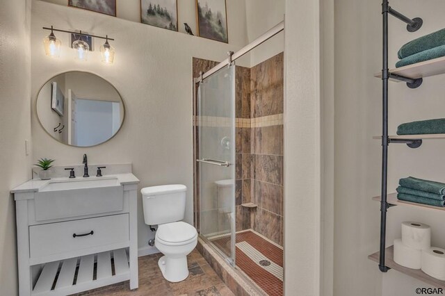 bathroom with vanity, a shower with shower door, and toilet