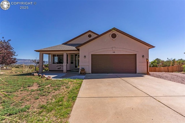 view of front of house with fence, a garage, driveway, and stucco siding