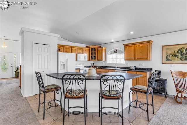 kitchen featuring white appliances, glass insert cabinets, dark countertops, a kitchen breakfast bar, and a center island