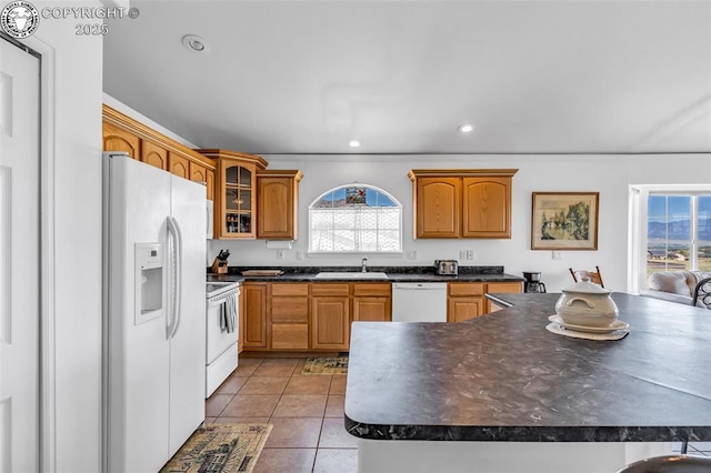 kitchen featuring white appliances, a healthy amount of sunlight, dark countertops, and a sink