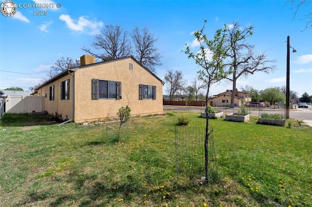 1815 N 10th St, Canon City, CO 81212 - view of home's exterior with stucco siding, a lawn, a garden, fence, and a chimney
