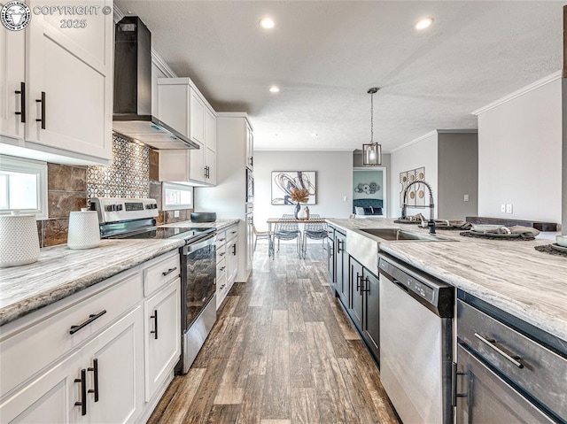 kitchen with white cabinetry, sink, light stone counters, stainless steel appliances, and wall chimney exhaust hood