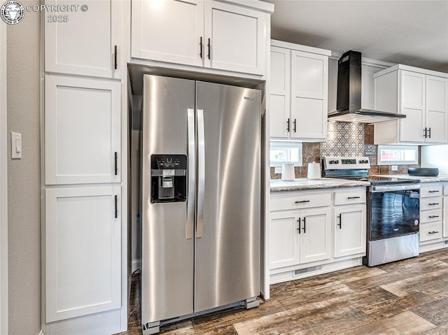 kitchen with wall chimney exhaust hood, white cabinetry, dark hardwood / wood-style floors, stainless steel appliances, and decorative backsplash