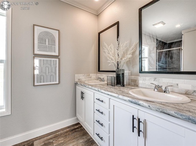 bathroom featuring vanity, wood-type flooring, ornamental molding, a healthy amount of sunlight, and a shower with shower door