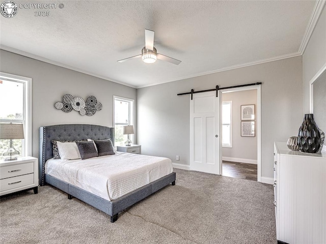 carpeted bedroom with ceiling fan, ornamental molding, a barn door, and a textured ceiling