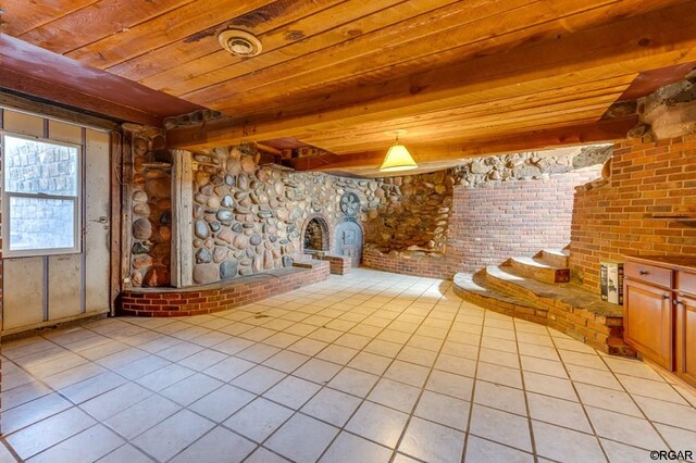 interior space featuring light tile patterned flooring, a large fireplace, wooden ceiling, and beam ceiling