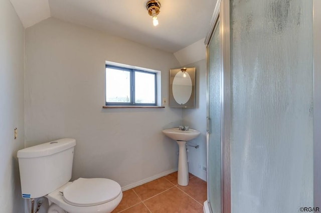 bathroom featuring lofted ceiling, toilet, tile patterned flooring, and a shower