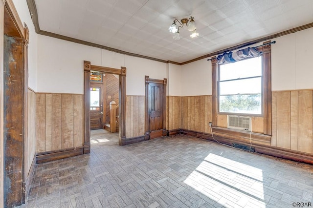 spare room with plenty of natural light, ornamental molding, and parquet flooring