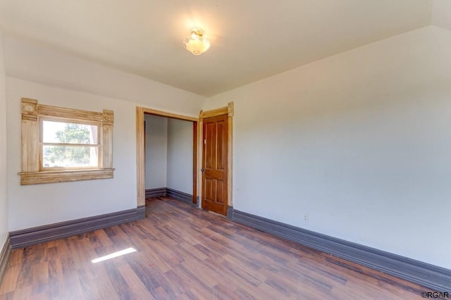 unfurnished bedroom with dark hardwood / wood-style floors, vaulted ceiling, and a closet