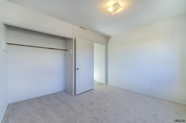 unfurnished bedroom featuring light colored carpet and a closet