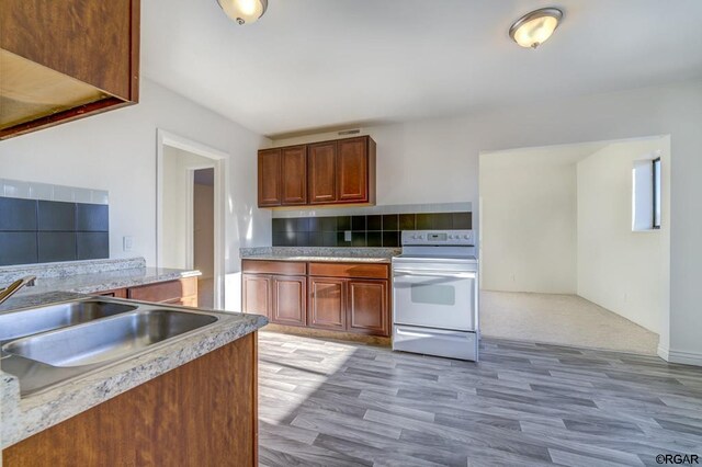 kitchen with tasteful backsplash, sink, white electric range, and light hardwood / wood-style flooring